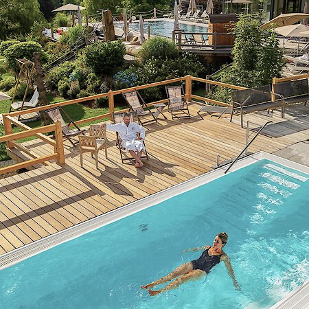 Ein paar gleitet im wohlig warmen Solepool im Freien. Wellnesshotel Riedlberg
