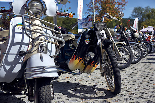 Auffälliges Moped mit Flammendekor neben einem weißen Roller aufgereiht beim Moped-Treffen im JOSKA Glasparadies in Bodenmais.
